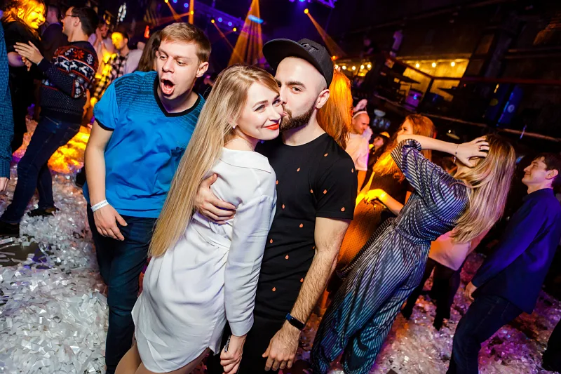 Friends hugging and laughing on the dance floor among confetti