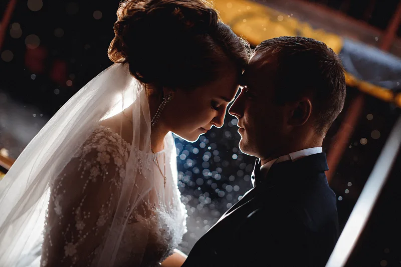 Bride and groom forehead to forehead under the veil in evening light